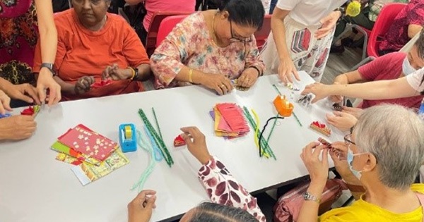 Seniors, along with attendees, engage with one other during the Ang Bao Fish craft-making session.