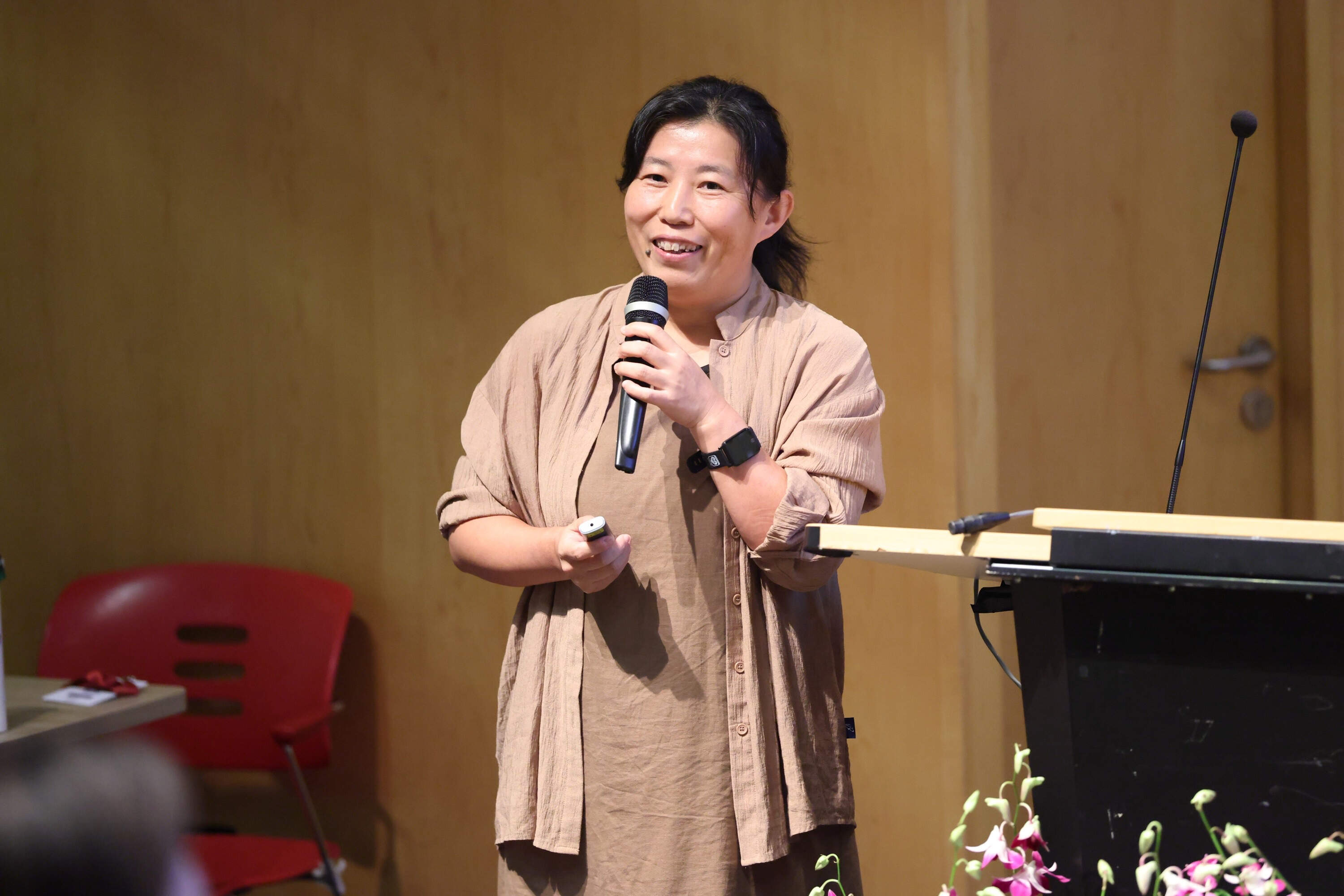 Speaker smiling while holding a microphone during a presentation