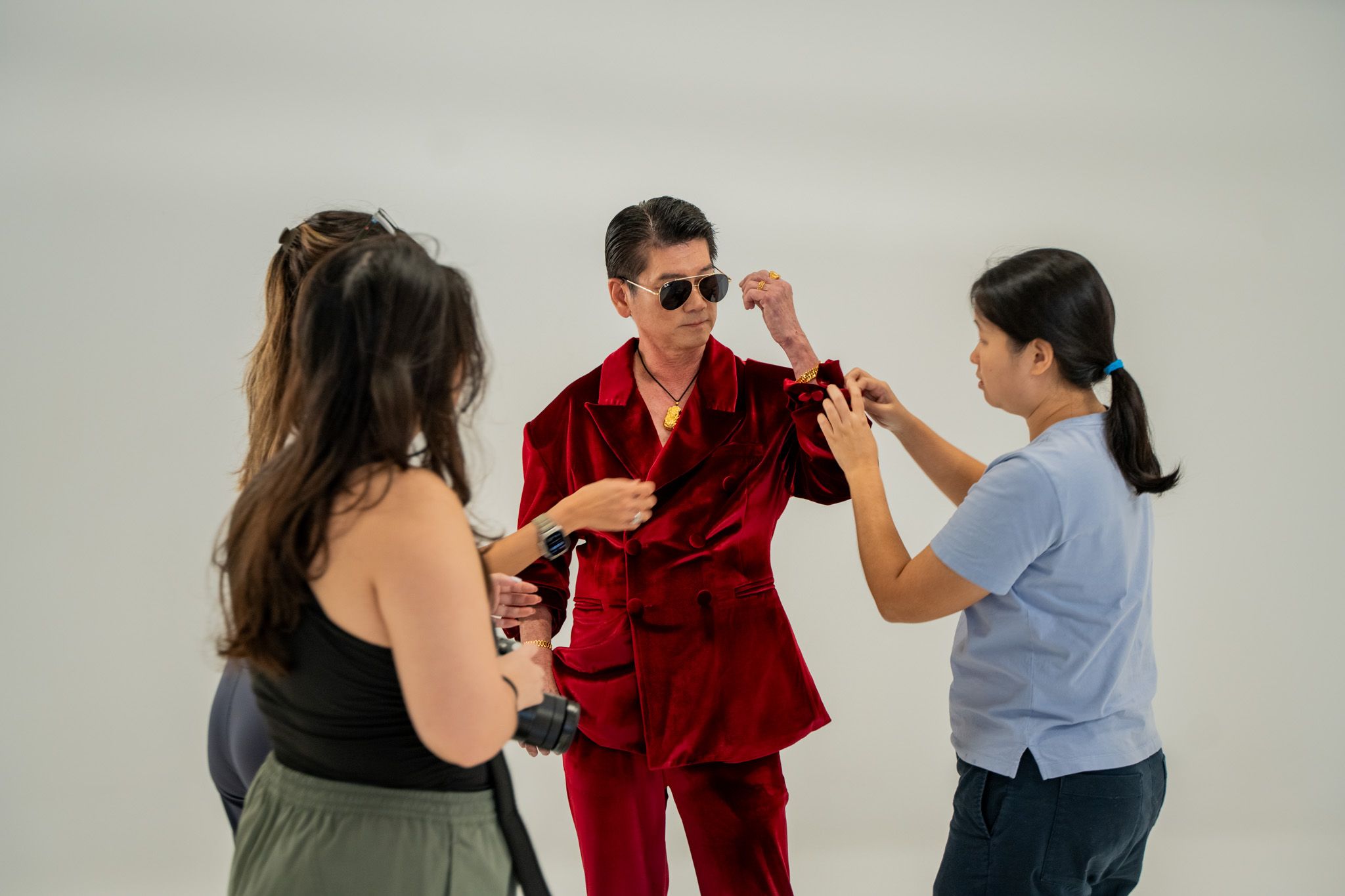 A group of people standing around a man wearing a red suit indoors, interacting and possibly dancing.