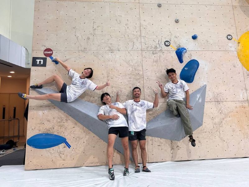 A team photo of four ODAIG climbers posed against the bouldering wall A team photo of four ODAIG climbers posed against the bouldering wall