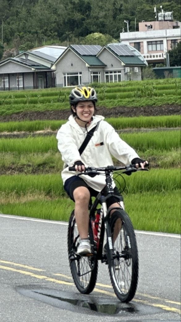 Chew Zhi Xuan (Year 3, English Language and Literature Student) cycles with a smile along the scenic Brown Avenue (伯郎大道) in Taitung on the way to visit the iconic “solo” tree at Taitung.