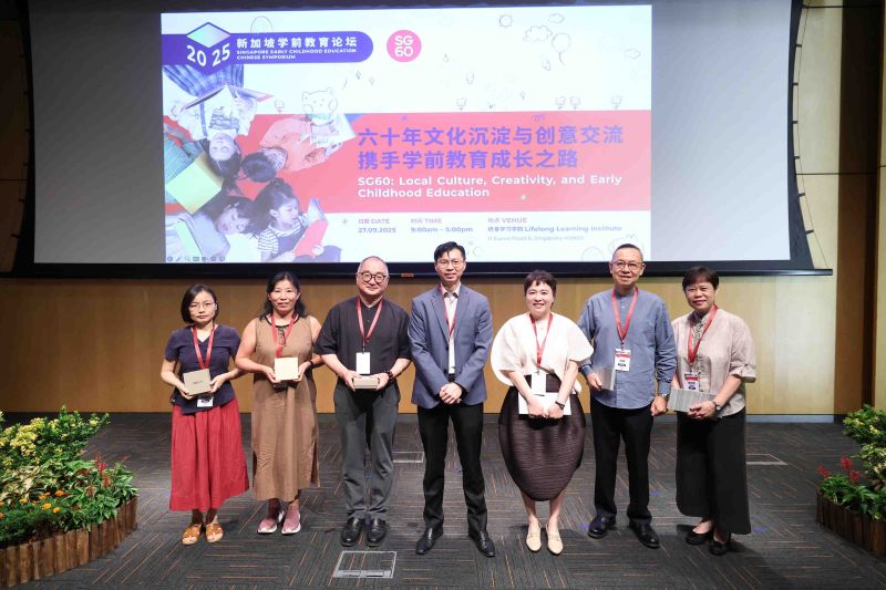 Group of people standing in front of a symposium banner on stage