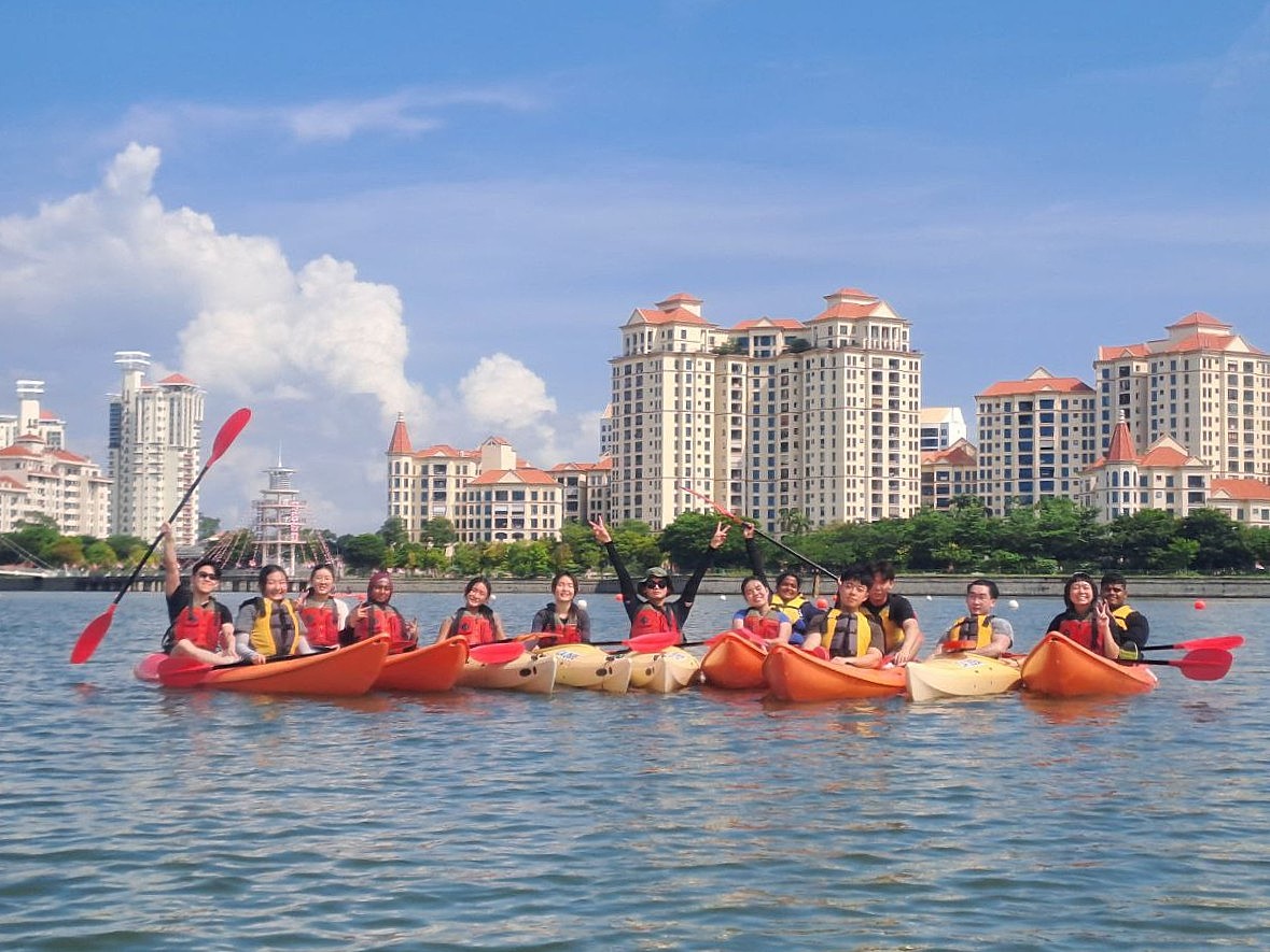 Participants and EXCO facilitators coming together as a raft in their kayaks, striking a fun group pose that captures teamwork and the adventurous spirit of the day.