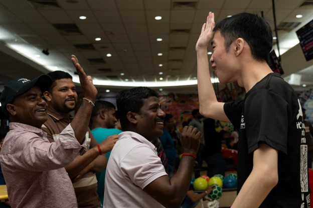 Migrant workers and student volunteers exchange high-fives, showing that camaraderie goes beyond competition Migrant workers and student volunteers exchange high-fives, showing that camaraderie goes beyond competition