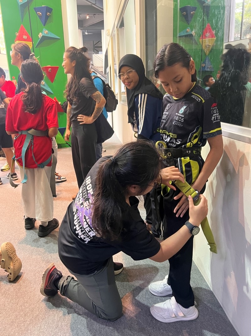 Lim Kym Suan, Esther assists a girl with her harness as the group gears up for rock climbing on Day 2, full of smiles and excitement