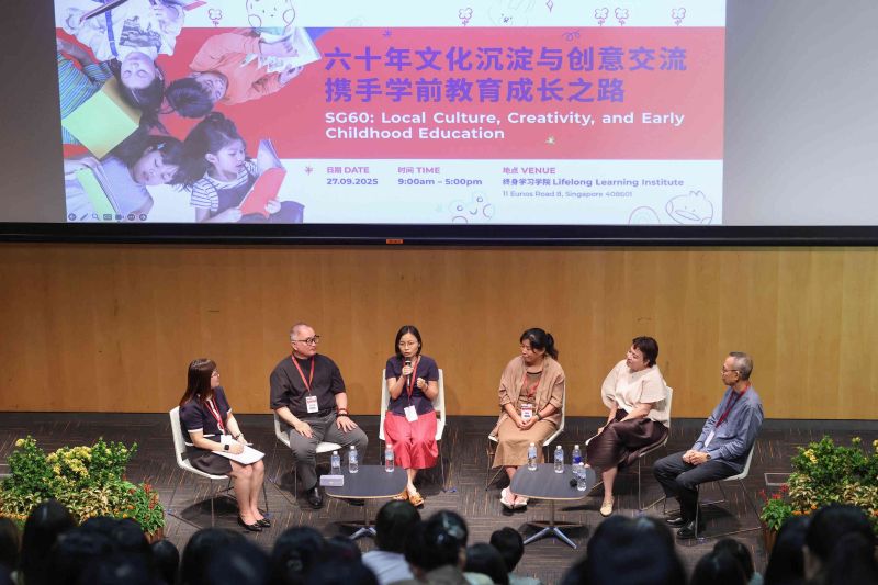 Panel discussion at SG60 event on stage with five speakers and audience