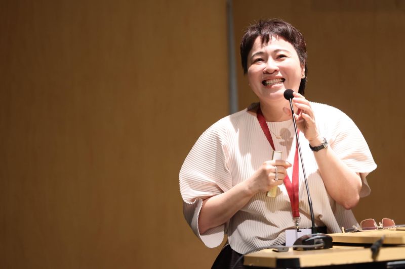 Person smiling while speaking at a podium with a microphone