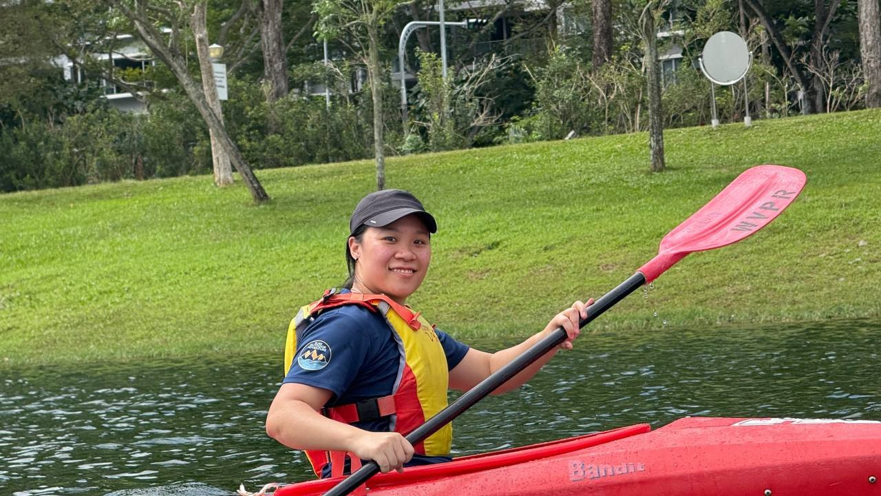 Charlotte Yang, SUSS staff and alumna, poses on her kayak with her paddle in hand.
