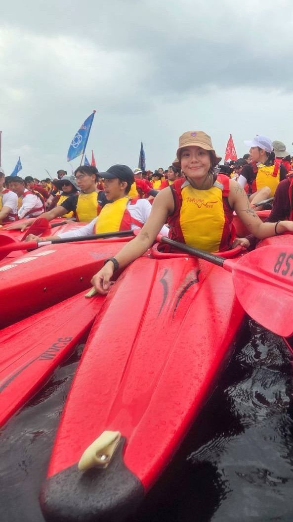 Katherine Goh Kai Ting flashes a warm smile at the camera as she holds on to the surrounding kayaks, helping to keep the raft steady on the water.