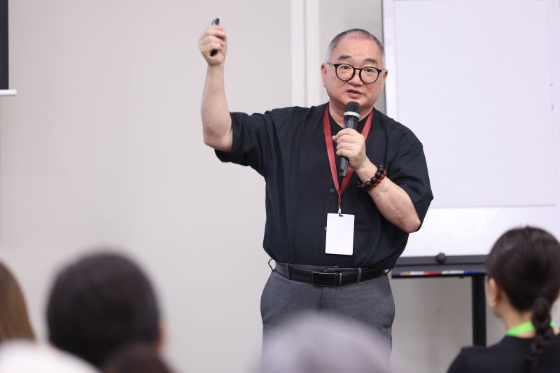 Speaker with microphone and lanyard presenting to an audience
