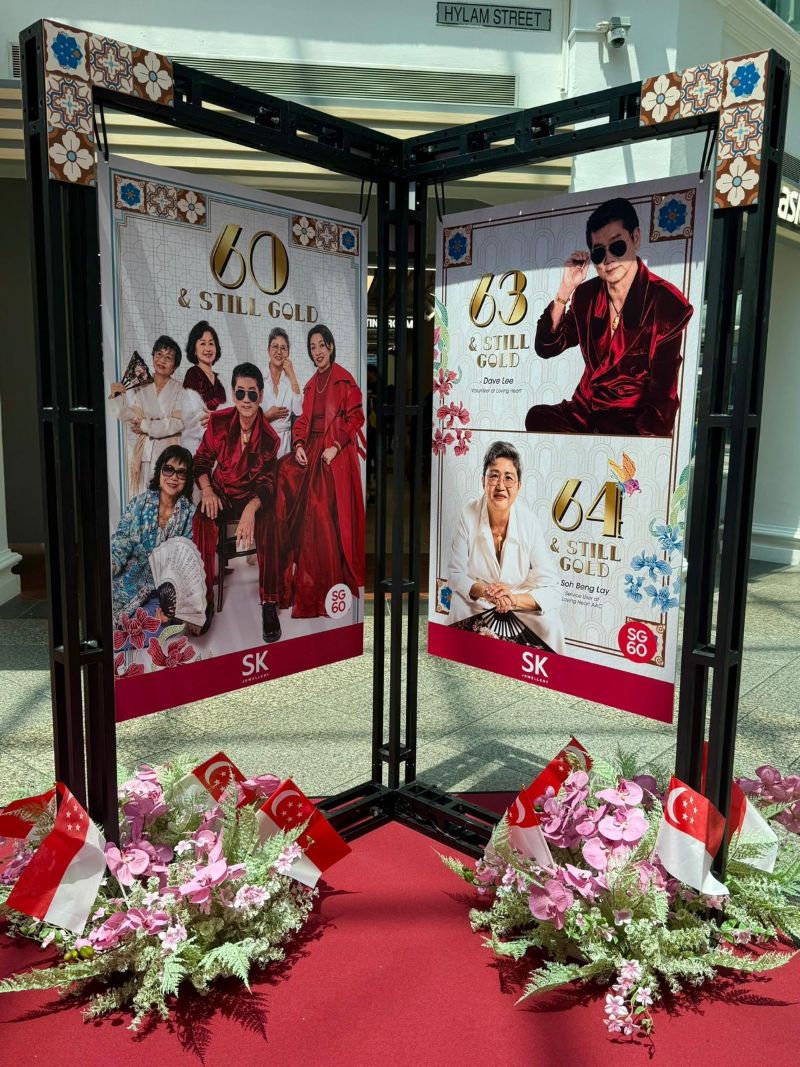 Two large posters display 60 & Still Gold and 63 & Still Gold with vibrant decorations and floral arrangements in front.