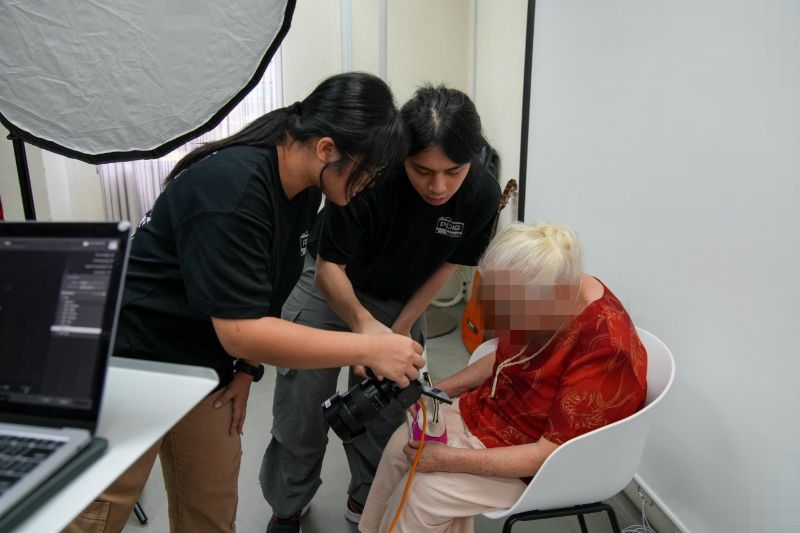 Yuan Ting (left) and Zack (right) showing beneficiaries their photos for them to review and check how they look in the photosn
