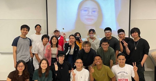 Participants gather for a group photo, while speaker Yen Phan joins virtually from Finland