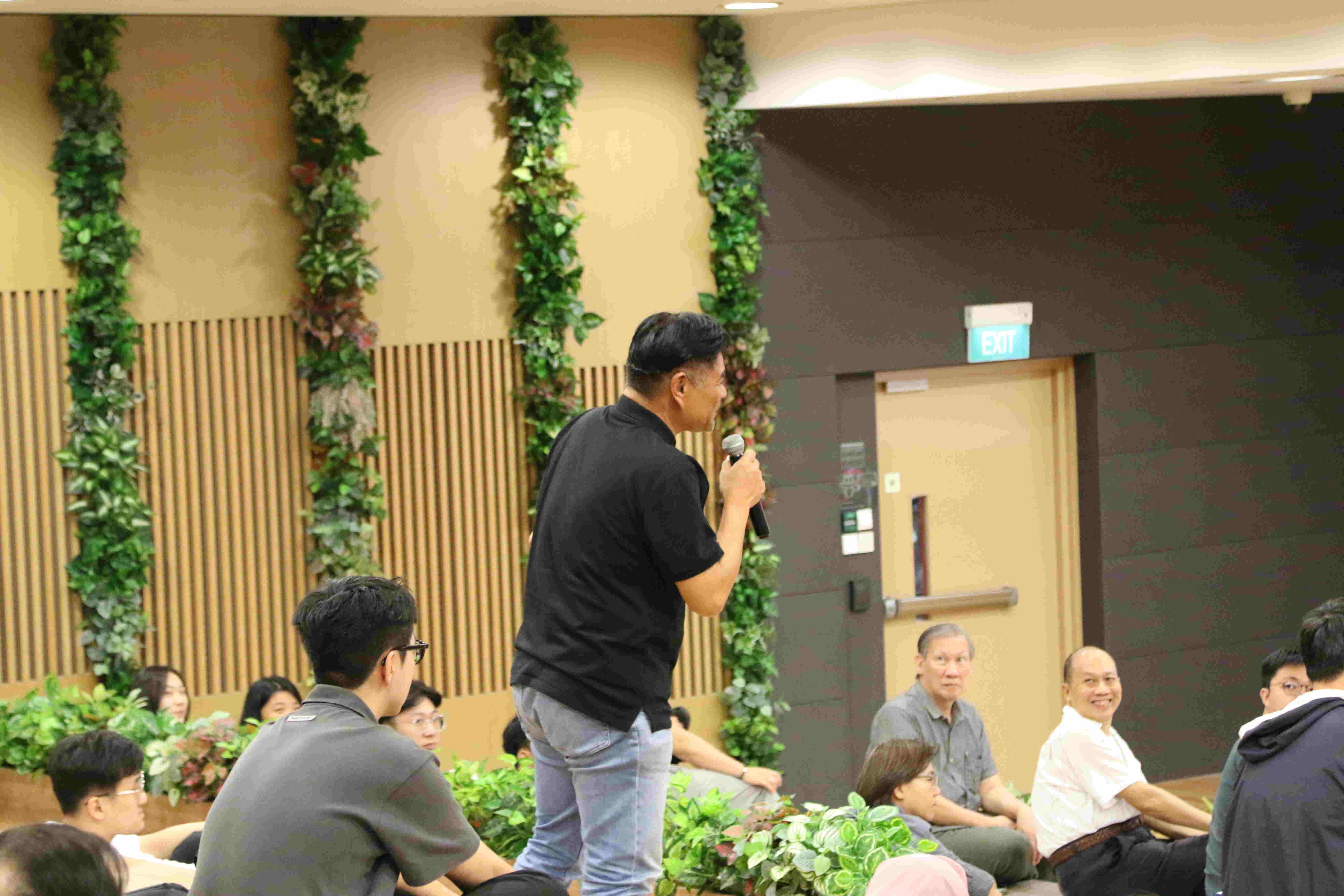 Person speaking into a microphone in a seated audience