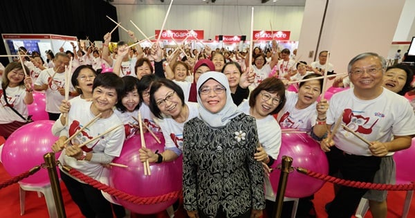 The World Ageing Festival 2024’s opening drum ensemble, comprising participants from all walks of life, pose for a photo with SUSS Chancellor, Mdm Halimah