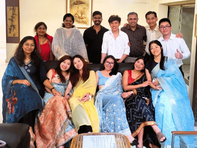 Group of people posing for a photo the women are all wearing Sari 