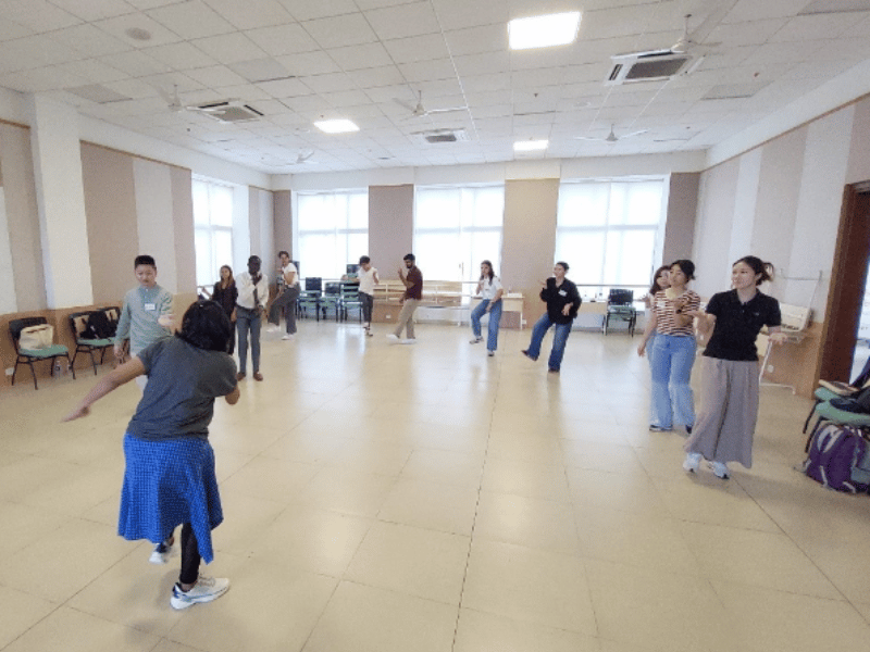 Group of people in a circle learning a dance