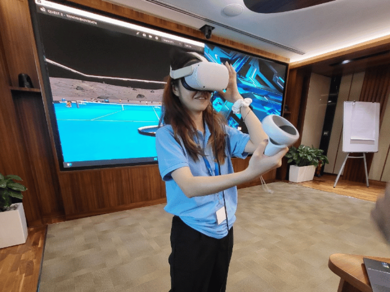 A girl wearing a VR face goggles and playing a tennis game