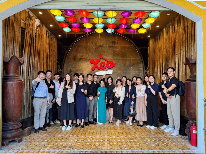 Group of people posing in front of a Xeo sign