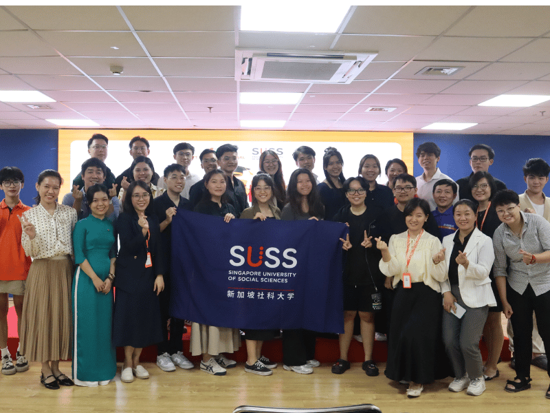 Group of people posing holding a SUSS school banner 
