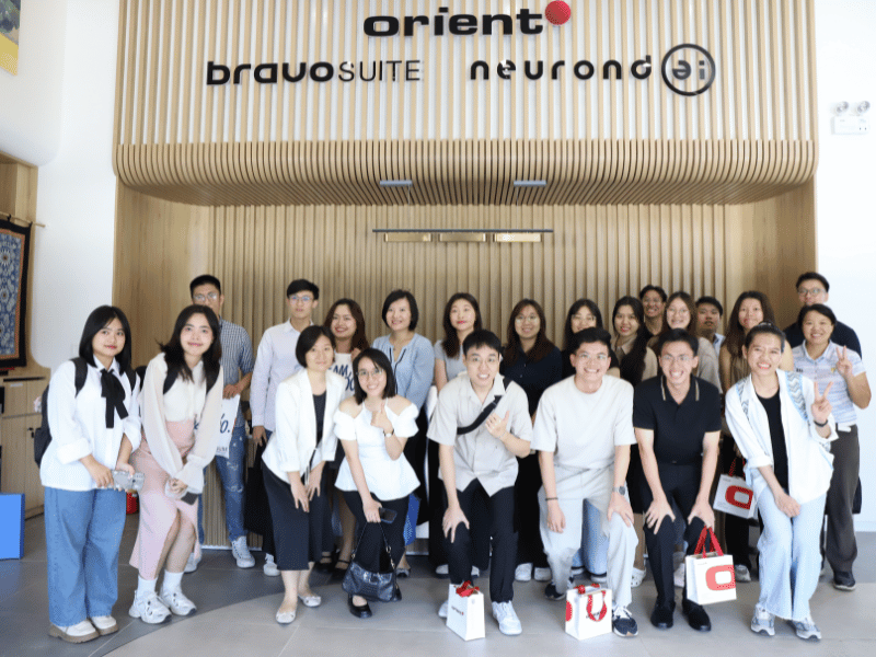 Group of people posing in front of Orient sign