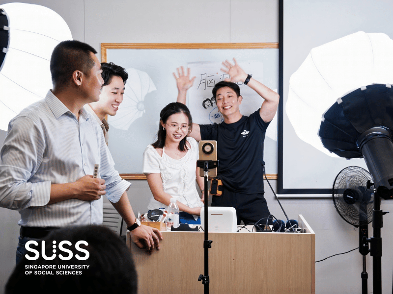 4 people at a shoot set with lights pointed at them and a phone in front of them 