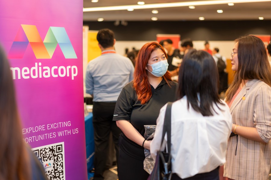 Attendees speaking with MediCorp representatives at a SUSS career fair recruitment booth.